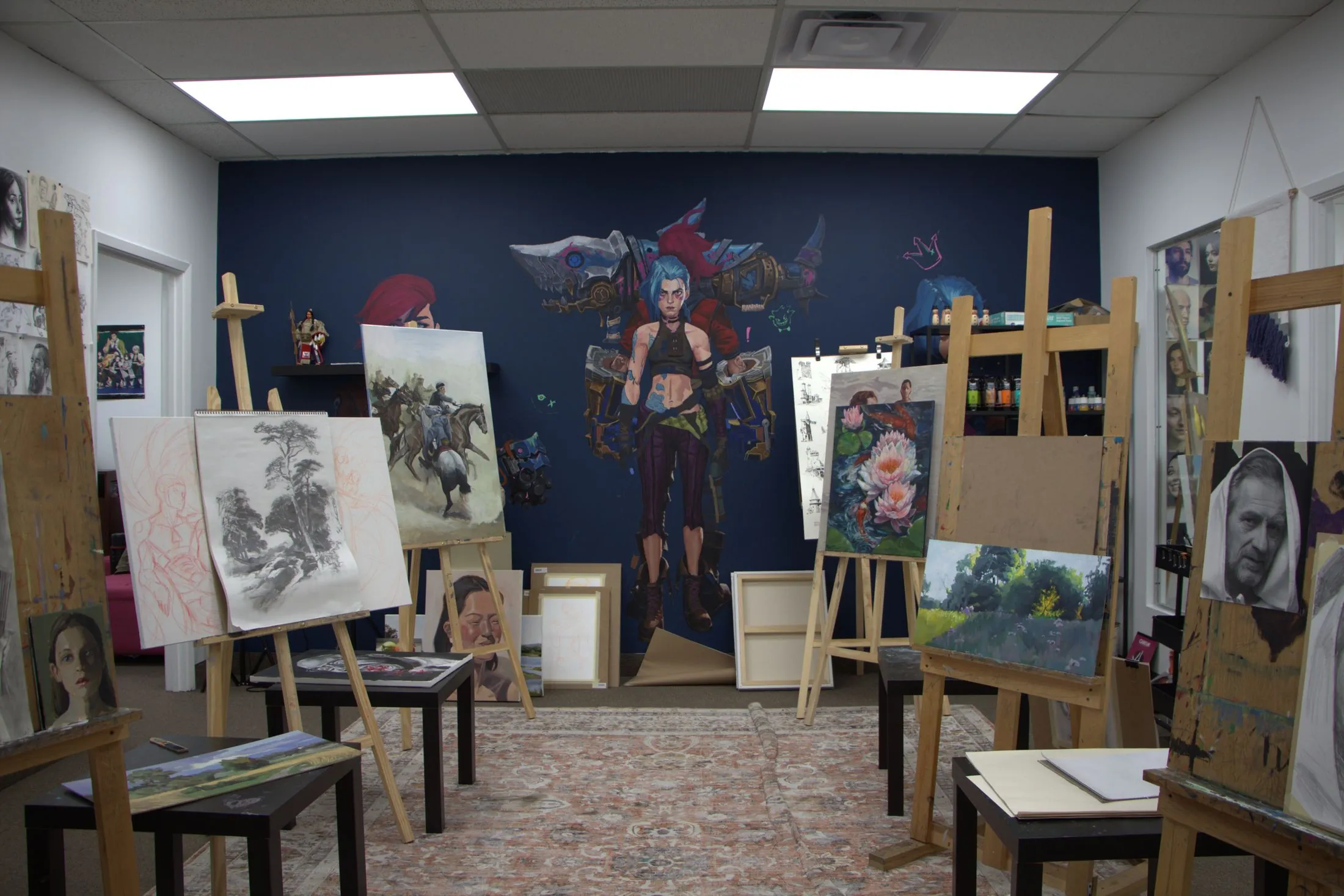 The Topaz Art Academy studio, with easels of student work in front of a large painted mural