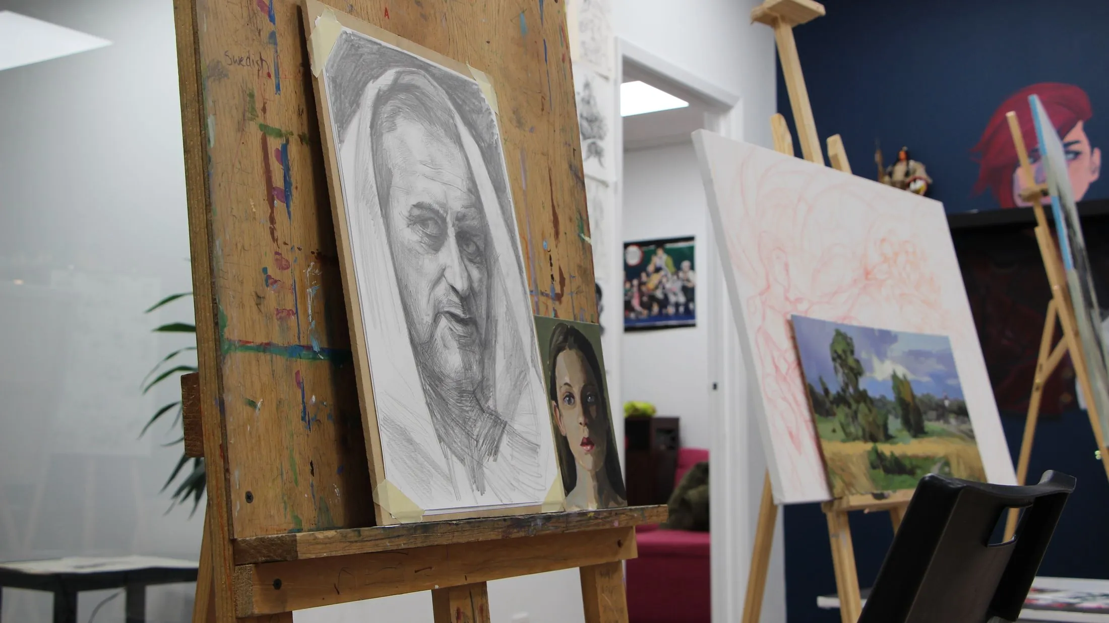 A graphite portrait drawing on an easel in the studio
